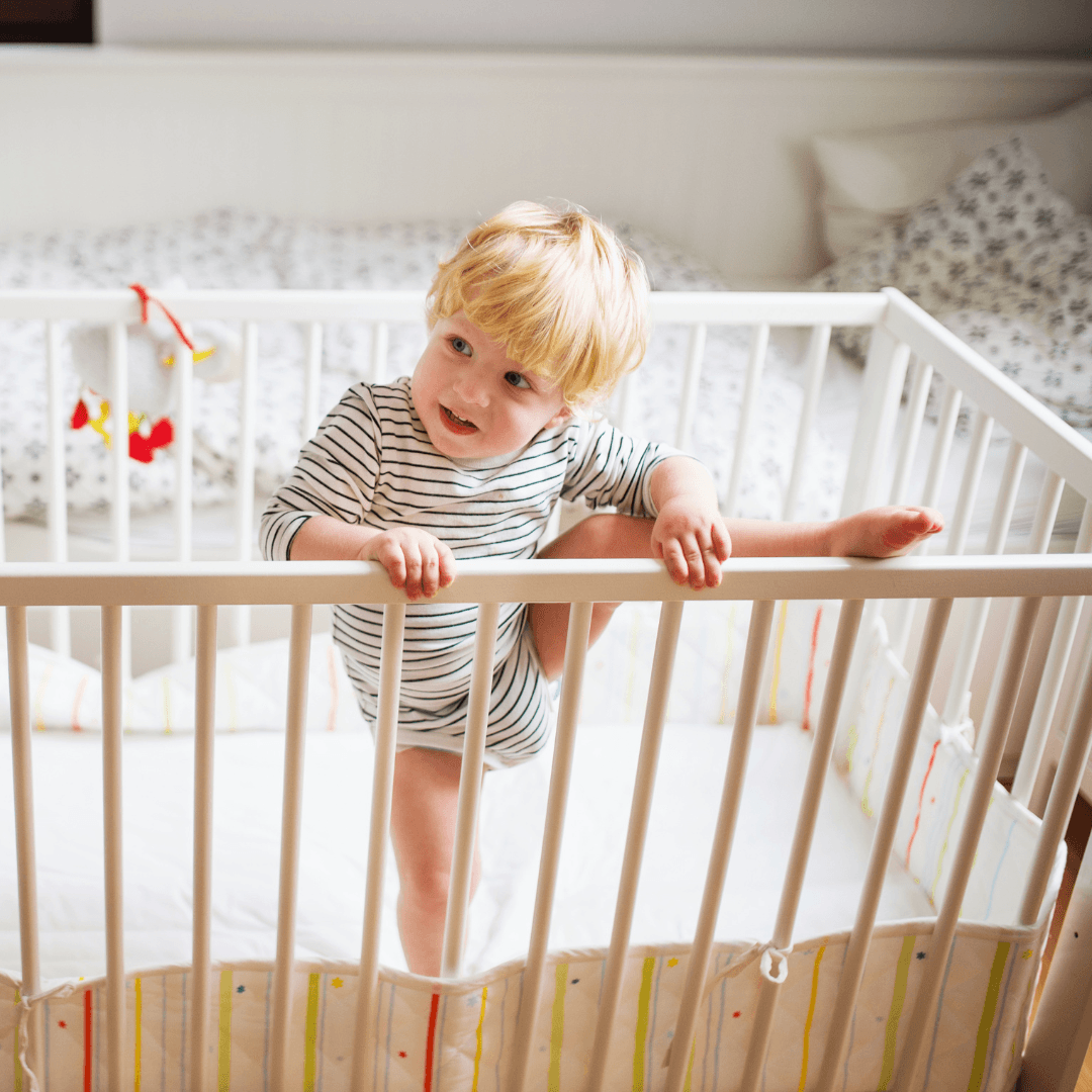 Un enfant debout dans son lit à barreaux